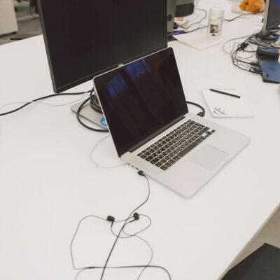 A contemporary office workspace featuring a laptop, monitor, and earbuds on a desk.
