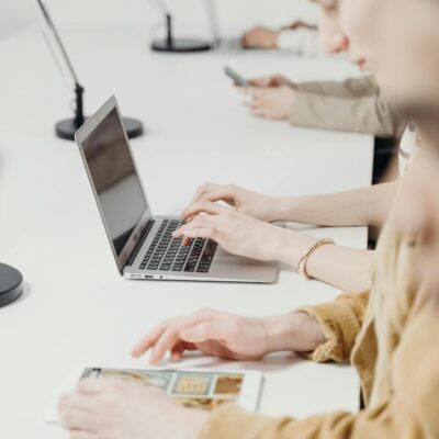 Team of professionals working on laptops and tablets in modern office setting.