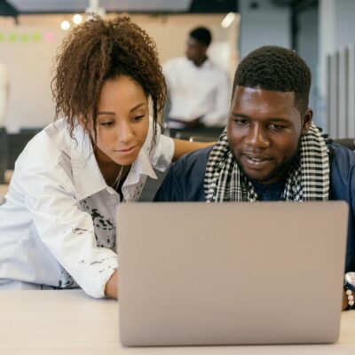 Two colleagues working together on a laptop in a contemporary office environment.